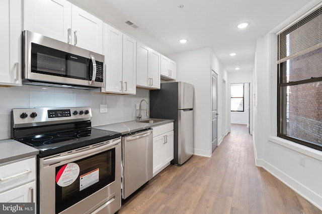 kitchen featuring stainless steel appliances, light wood-type flooring, and white cabinetry