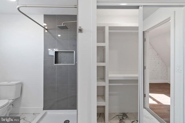 bathroom featuring tile flooring, toilet, and tiled shower