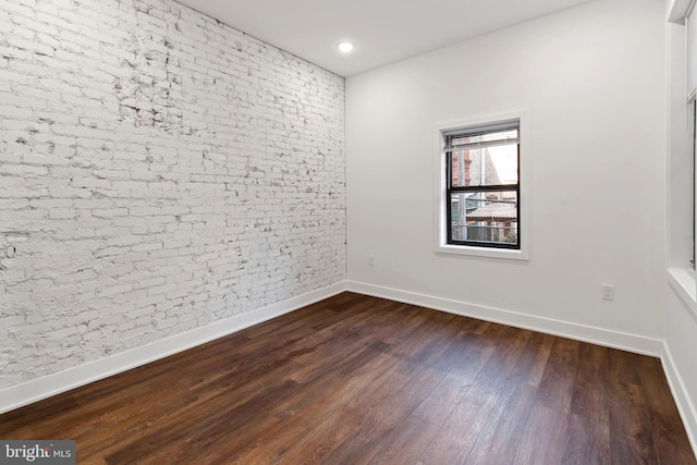 empty room with brick wall and dark hardwood / wood-style floors