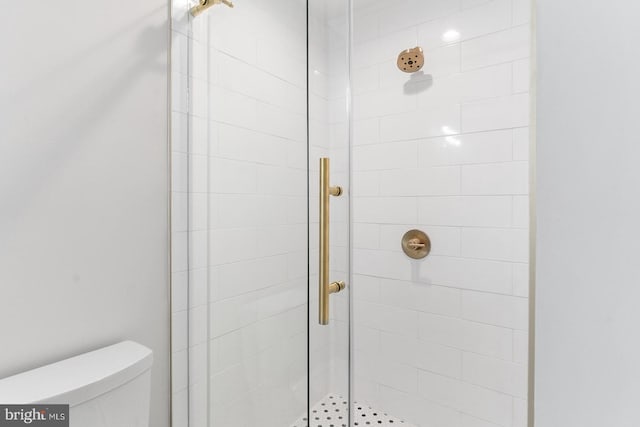 bathroom featuring a shower with shower door and toilet