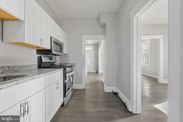 kitchen with dark hardwood / wood-style floors, white cabinetry, appliances with stainless steel finishes, and light stone countertops