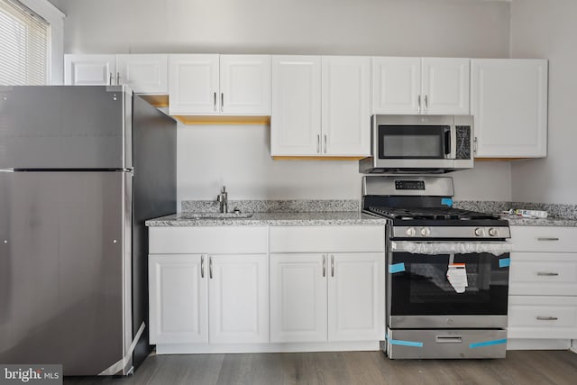 kitchen featuring light stone countertops, white cabinetry, dark wood-type flooring, sink, and stainless steel appliances