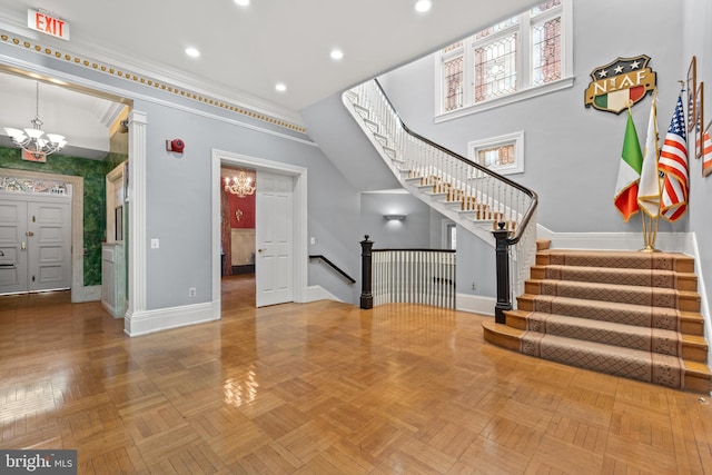 interior space with a notable chandelier, light parquet floors, and a towering ceiling