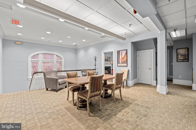 dining room featuring a drop ceiling, ornamental molding, and light carpet