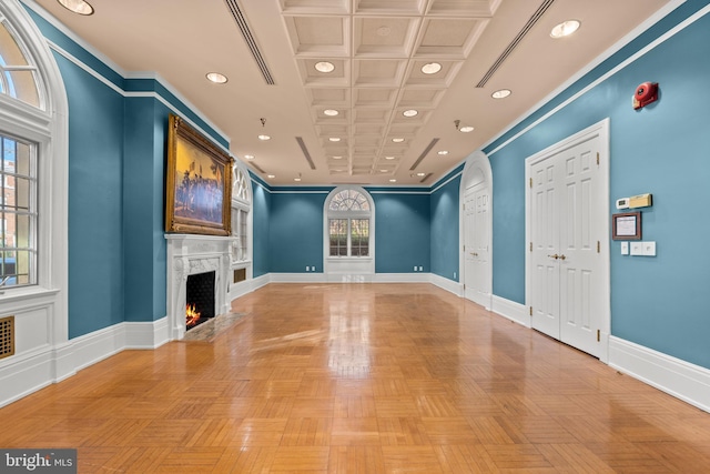 unfurnished living room with coffered ceiling, light parquet floors, a high end fireplace, and ornamental molding