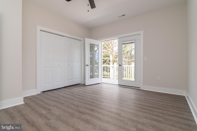 unfurnished bedroom with a closet, hardwood / wood-style floors, access to exterior, french doors, and ceiling fan