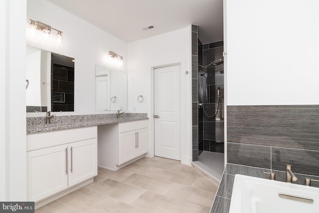 bathroom with tiled shower, vanity, and tile patterned flooring