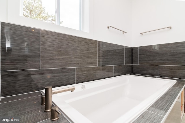 bathroom featuring tiled bath and tile walls