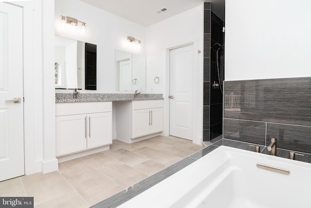 bathroom with vanity, tile patterned flooring, and a bathtub