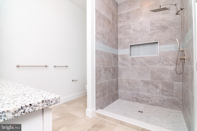 bathroom with tile patterned floors, toilet, and a tile shower