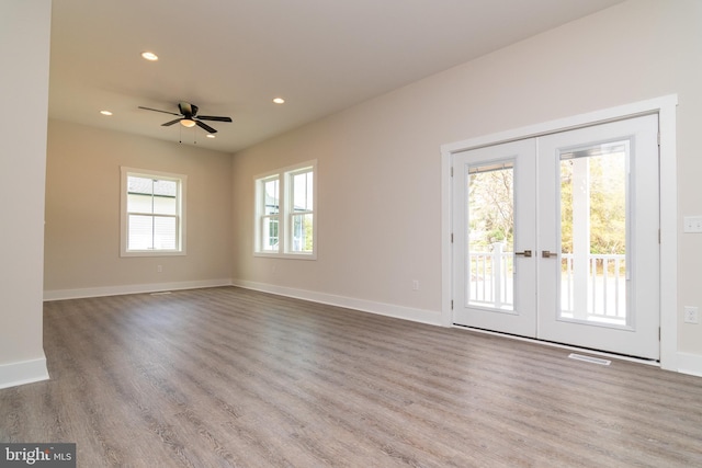 spare room with ceiling fan, a healthy amount of sunlight, light hardwood / wood-style flooring, and french doors