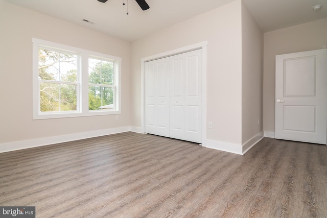 unfurnished bedroom with ceiling fan, hardwood / wood-style floors, and a closet