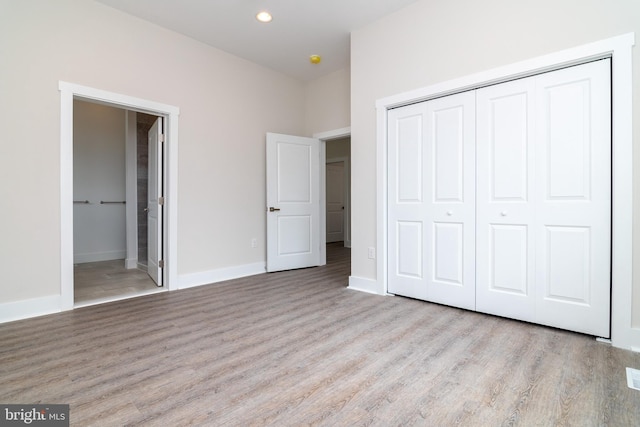 unfurnished bedroom featuring light hardwood / wood-style floors, connected bathroom, and a closet