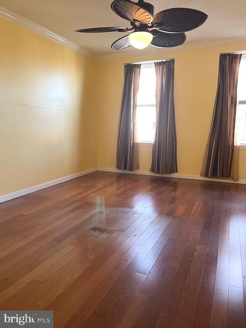 empty room featuring ornamental molding, dark hardwood / wood-style flooring, and ceiling fan