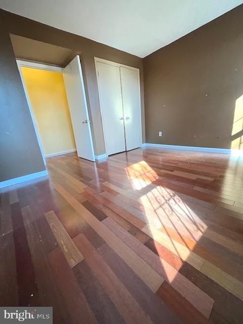 unfurnished bedroom with a closet and dark hardwood / wood-style floors