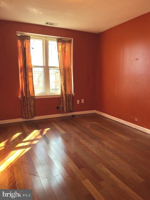 unfurnished room with dark wood-type flooring