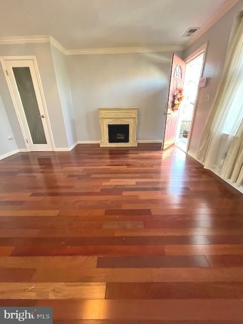 unfurnished living room featuring crown molding and dark wood-type flooring