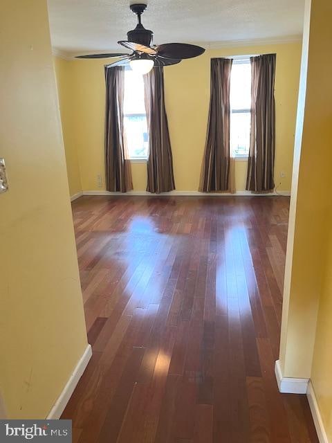 unfurnished room featuring a healthy amount of sunlight, ceiling fan, and dark hardwood / wood-style flooring