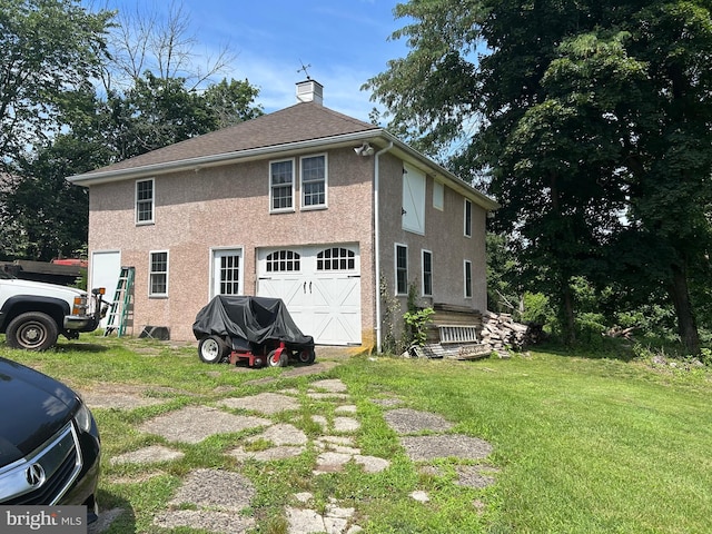 back of property featuring a garage and a lawn