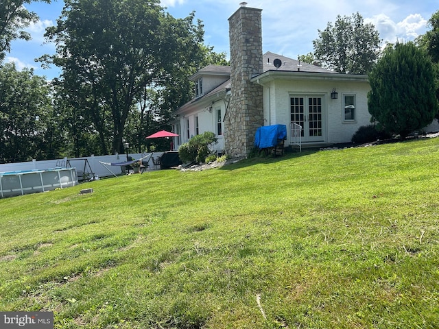 rear view of house with french doors and a lawn