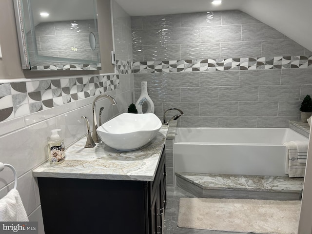 bathroom with vaulted ceiling, tile walls, vanity with extensive cabinet space, backsplash, and tile flooring