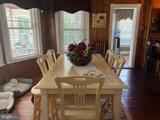 dining room with dark hardwood / wood-style flooring, wooden walls, and radiator