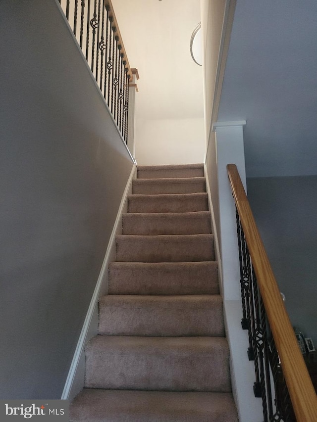 stairway featuring dark colored carpet