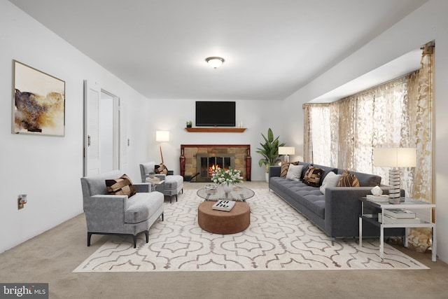 carpeted living room with a stone fireplace