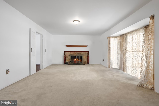 unfurnished living room with carpet flooring and a stone fireplace