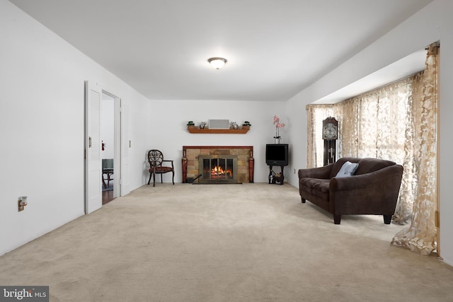 living area featuring light carpet and a fireplace