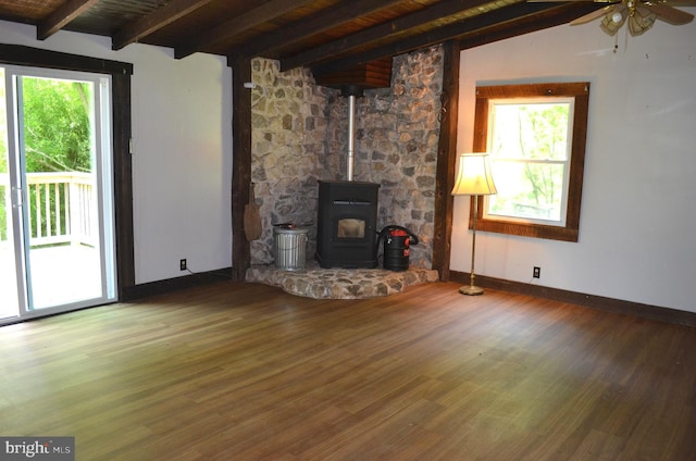 unfurnished living room with a wood stove, a wealth of natural light, ceiling fan, and hardwood / wood-style floors