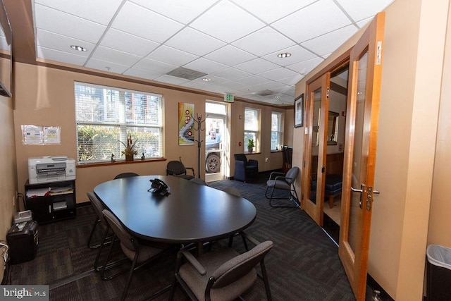 dining space featuring a wealth of natural light, dark colored carpet, and a paneled ceiling