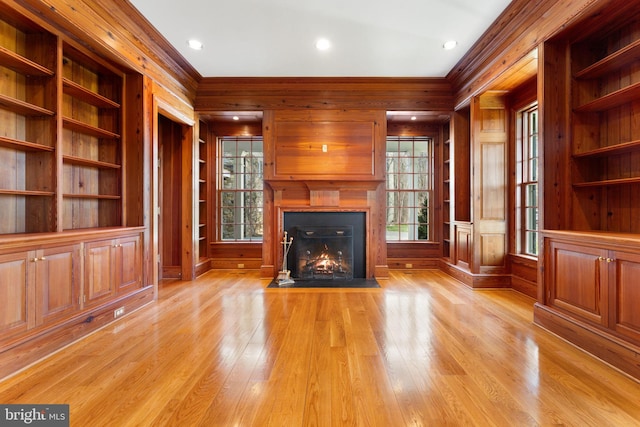 unfurnished living room with wood walls, light hardwood / wood-style flooring, and built in shelves