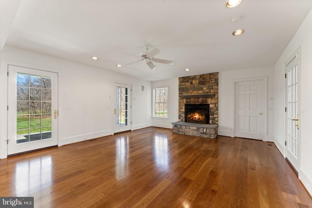 unfurnished living room featuring plenty of natural light, a fireplace, ceiling fan, and dark hardwood / wood-style flooring