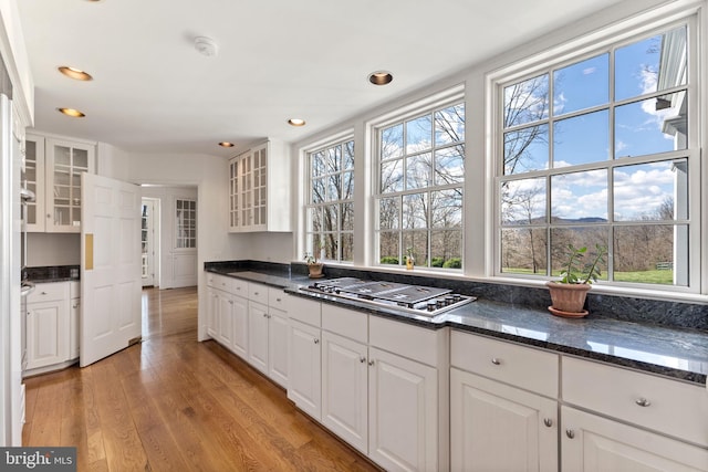 kitchen featuring light hardwood / wood-style floors, stainless steel gas cooktop, white cabinets, and dark stone countertops