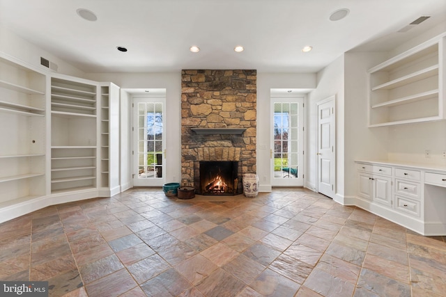 unfurnished living room with light tile floors, a stone fireplace, and a healthy amount of sunlight