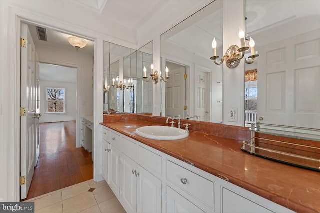 bathroom featuring an inviting chandelier, large vanity, and wood-type flooring