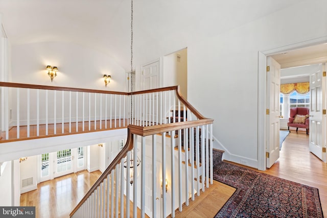 staircase featuring light hardwood / wood-style flooring, plenty of natural light, and high vaulted ceiling