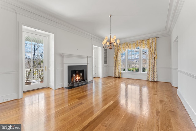 unfurnished living room with a notable chandelier, ornamental molding, and light hardwood / wood-style flooring