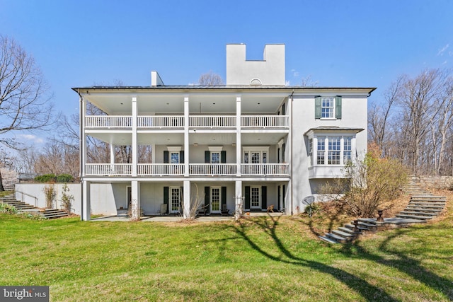 rear view of property with a balcony and a lawn