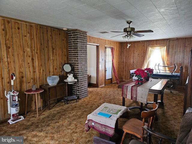 miscellaneous room featuring ceiling fan, dark carpet, brick wall, and wood walls