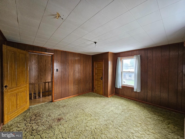 spare room with wood walls and light colored carpet