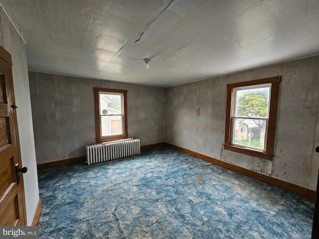 spare room featuring dark carpet and radiator heating unit