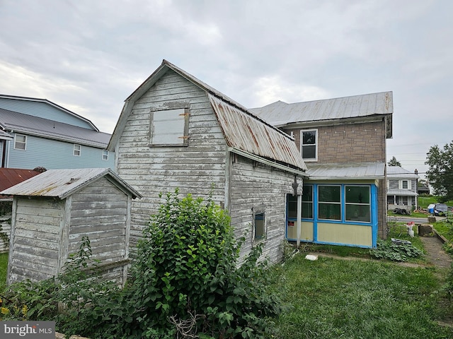 back of house with a yard and a shed