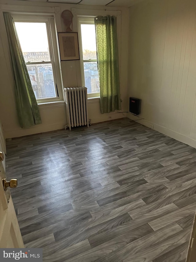 unfurnished room featuring radiator and dark hardwood / wood-style floors