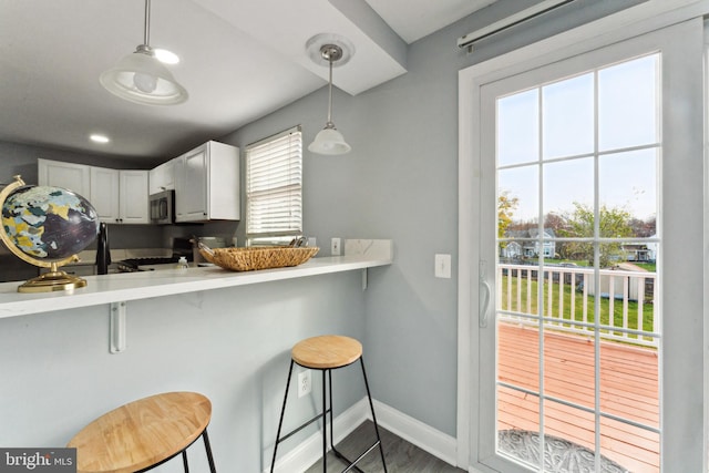 kitchen featuring a breakfast bar, white cabinetry, and a wealth of natural light