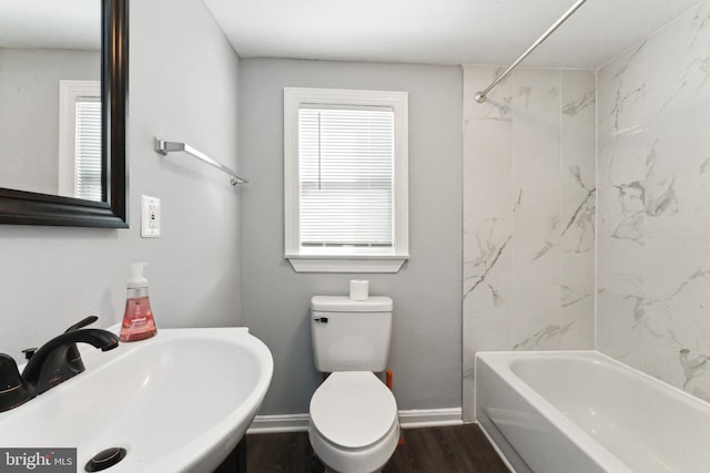 full bathroom featuring hardwood / wood-style flooring, tiled shower / bath combo, toilet, and sink