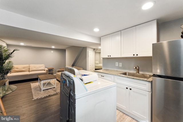 kitchen with sink, dark hardwood / wood-style floors, stainless steel refrigerator, white cabinetry, and washer / clothes dryer