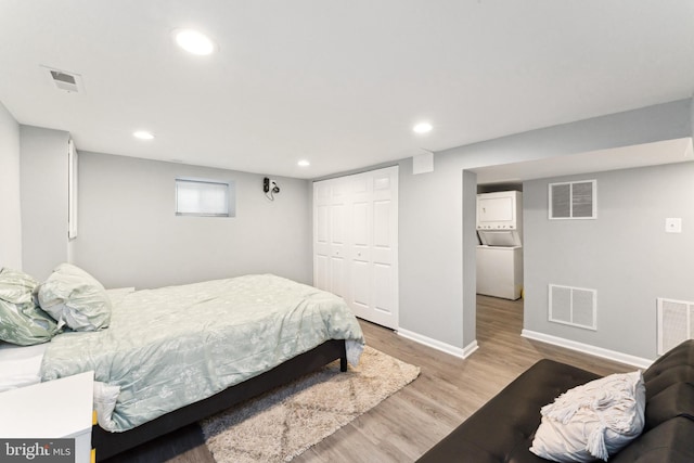 bedroom featuring stacked washer / dryer, a closet, and light hardwood / wood-style floors