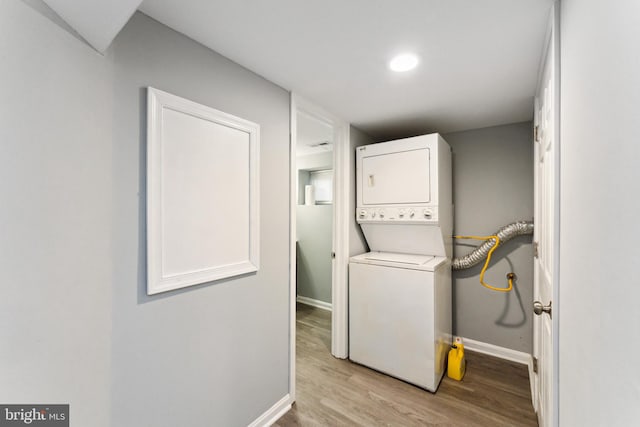 washroom featuring stacked washer / drying machine and light hardwood / wood-style flooring